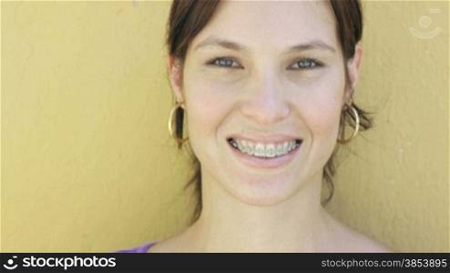 Attractive young woman with dental braces smiling at camera