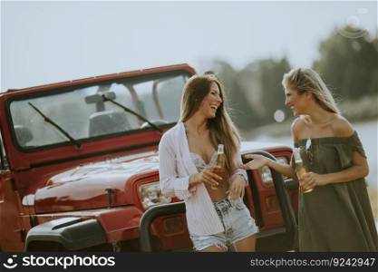 Attractive young women having fun by  a convertible car on a summer day