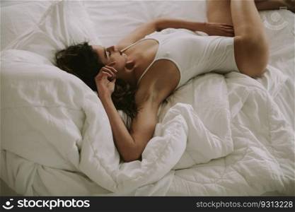 Attracttive young woman lies in white bed