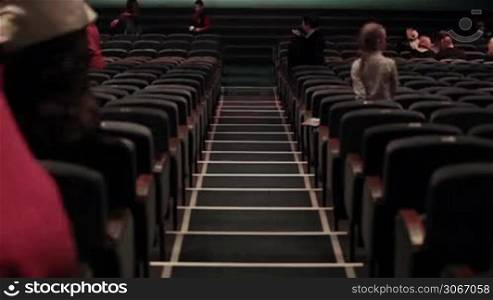 Audience fills the theatre. Defocused people shot from back. Time lapse.