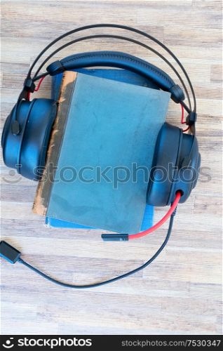 Audio book concept. Black headphones and pile of books on wooden table. Top view with copy space.. Audio book concept
