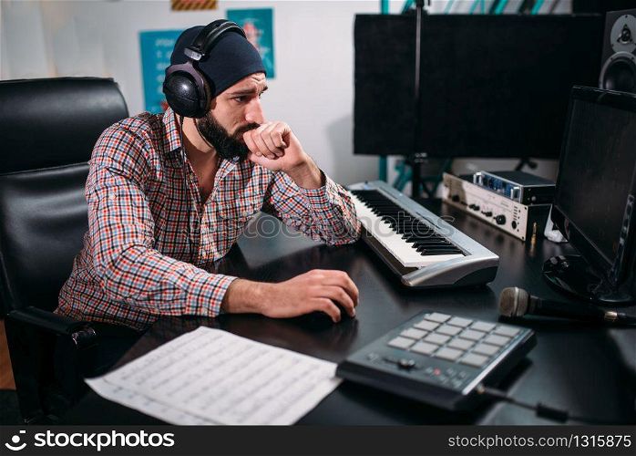 Audio engineer in headphones work with musical keyboard in studio. Professional digital sound record technology
