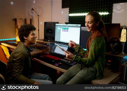 Audio engineer with young girl singer working in music recording studio using mobile tablet. Audio engineer with young singer working in music recording studio