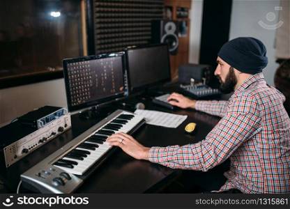 Audio engineer work with musical keyboard in studio. Professional digital sound recording technology