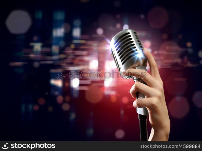 audio microphone retro style. Female hand holding a single retro microphone against colourful background