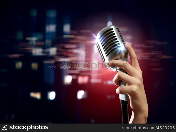 audio microphone retro style. Female hand holding a single retro microphone against colourful background