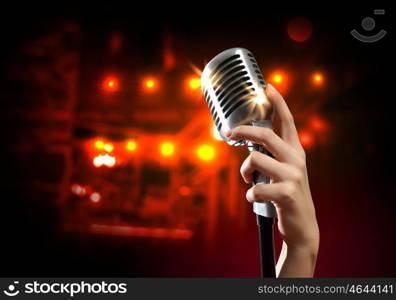 audio microphone retro style. Female hand holding a single retro microphone against colourful background