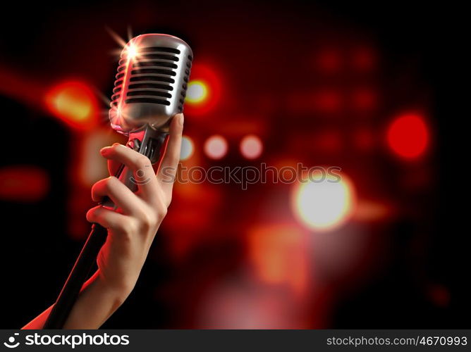 audio microphone retro style. Female hand holding a single retro microphone against colourful background