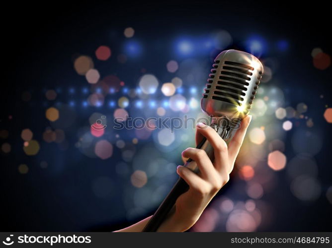 audio microphone retro style. Female hand holding a single retro microphone against colourful background