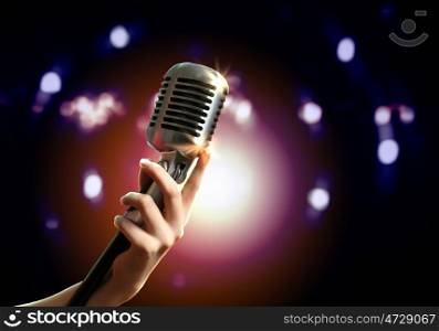 audio microphone retro style. Female hand holding a single retro microphone against colourful background