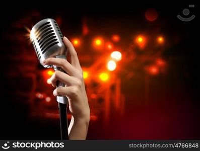 audio microphone retro style. Female hand holding a single retro microphone against colourful background
