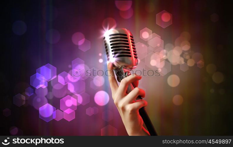 audio microphone retro style. Single retro microphone against colourful background with lights