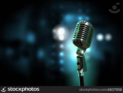 audio microphone retro style. Single retro microphone against colourful background with lights