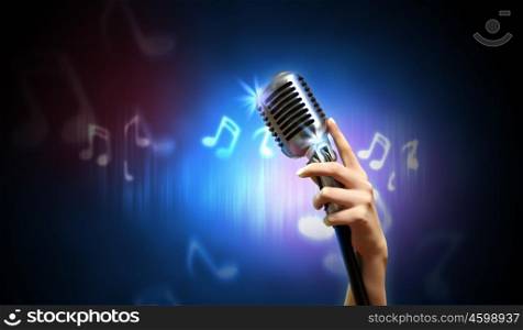 Audio microphone retro style. Single retro microphone against dark background with music notes