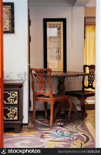 AUG 4, 2014 Bangkok, Thailand - Oriental chinese vintage wooden furniture, chairs, round table, carved wood cabinet in old house with mosaic floor