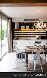 AUG 4, 2014 Hua Hin, THAILAND - Light tone furniture in dining area with white chandelier and pantry kitchen. Cozy contemporary home interior furnitures