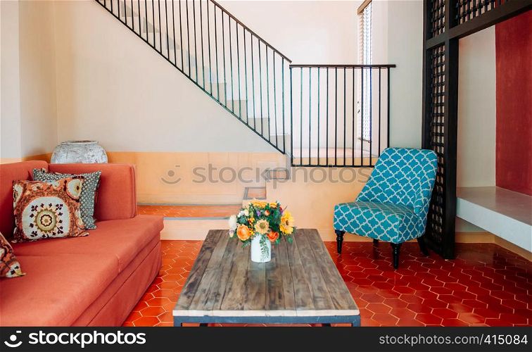 AUG 4, 2014 Hua Hin, THAILAND - Red fabric sofa couch, Asian style pillows, old wood table and colourfu;l armchair in living room. Cozy contemporary home interior furnitures