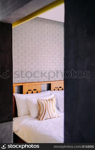 AUG 4, 2014 Hua Hin, THAILAND - Vintage cozy hotel room with bed, pillows, grey coloured brick wall. Contemporary country home decoration