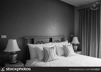 AUG 4, 2014 Hua Hin, THAILAND - Vintage cozy hotel room with bed, Chinaware ceramic lamp, pillows, wooden side table and dark coloured brick wall. Vintage country home decoration