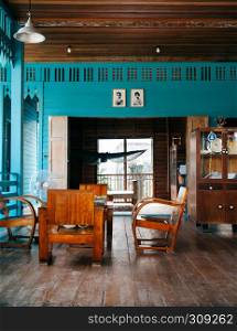 AUG 6, 2014 Bangkok, Thailand - Vintage wooden furniture, chairs, table, wood cabinet in old Thai country house with hard wood floor and bright coloured wall