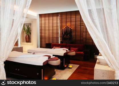 AUG 7, 2014 Hua Hin, THAILAND - Asian Thai tropical wellness Spa Concept, wood floor Spa room with massage beds, white curtains and Thai antique decorating items