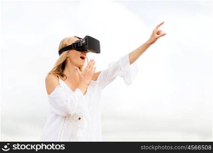augmented reality, gaming, summer holidays, technology and people concept - amazed young woman with virtual reality headset or 3d glasses pointing finger to something