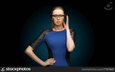 augmented reality, science and technology concept - beautiful woman in futuristic vr glasses over dark blue background. woman in virtual reality vr glasses