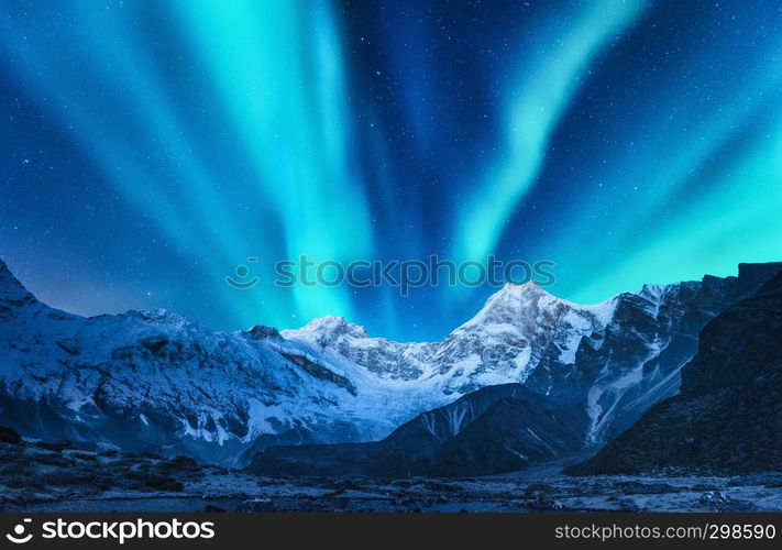 Aurora borealis above the snow covered mountain range in europe. Northern lights in winter. Night landscape with green polar lights and snowy mountains. Starry sky with aurora over the rocks. Space