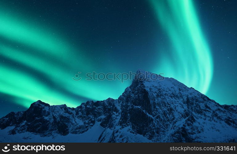 Aurora borealis above the snow covered mountain range in europe. Northern lights in winter. Night landscape with green polar lights and snowy mountains. Starry sky with aurora. Nature. Space