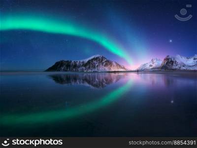 Aurora borealis and beach in Lofoten islands, Norway. Beautiful northern lights. Starry sky with polar lights. Night winter landscape with aurora, sea with sky reflection, city lights, snowy mountains