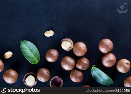 Australian macadamia nuts and green leaves on a black background. Australian macadamia nuts and green leaves on black background