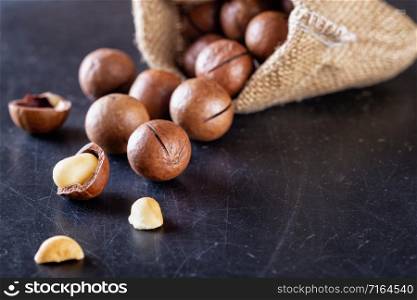 Australian macadamia nuts poured out of a bag on a black scratched table. Australian macadamia nuts poured out of bag on black table