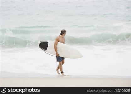 Australian surfer with surfboard on beach