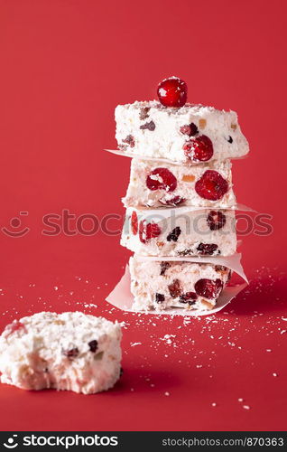 Australian Xmas traditional dessert, a white Christmas cakes, piled in a stack and an eaten piece, on a red background. Winter holidays festive sweets