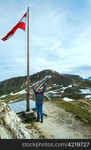 Austrian Flag above Alps mountain (Grossglockner High Alpine Road) and woman - tourist near