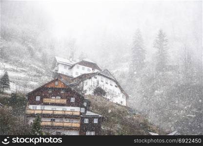 Austrian houses in the forest, on the Northern Limestone Alps, while heavy snowing covers it, located in Hallstatt, one of the World Heritage Sites in Austria.