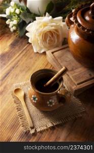 Authentic homemade mexican coffee (cafe de olla) served in traditional clay mug (Jarrito de barro) on rustic wooden table.