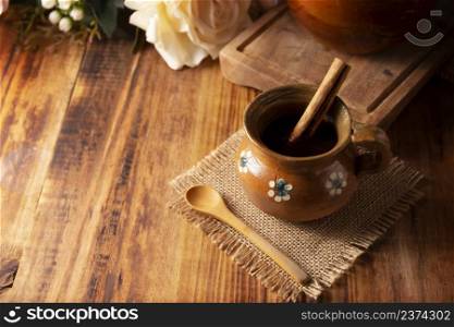 Authentic homemade mexican coffee (cafe de olla) served in traditional clay mug (Jarrito de barro) on rustic wooden table.
