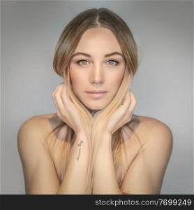 Authentic portrait of a beautiful blond woman isolated on gray background, genuine beauty of a young adult female, natural makeup and fashion look 