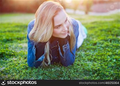 Authentic portrait of a pretty girl lying down on fresh green grass meadow, genuine beauty ofa young woman, enjoying spring nature and peaceful weekend in countryside . Pretty girl lying down on green grass