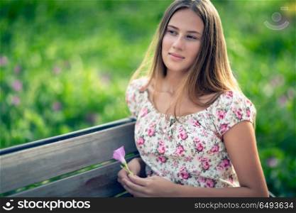 Authentic portrait of a young woman, beautiful student girl sitting on the bench in the park and relaxing, genuine beauty of youth. Authentic portrait of a young woman