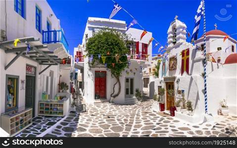 Authentic traditional Greece. Charming colorful floral streets of Mykonos island with fashion shops and little churches. Cyclades june 2021