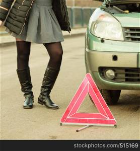 Auto assistance and insurance, troubles while traveling concept. Broken car and auto triangle on road, woman waiting for help.. Woman, broken car and auto triangle on road
