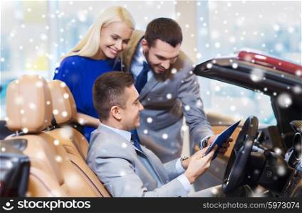 auto business, car sale, consumerism and people concept - happy couple and dealer in cabrio at auto show or salon over snow effect