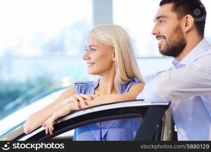 auto business, car sale, consumerism and people concept - happy couple buying car in auto show or salon