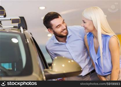 auto business, car sale, consumerism and people concept - happy couple buying car in auto show or salon