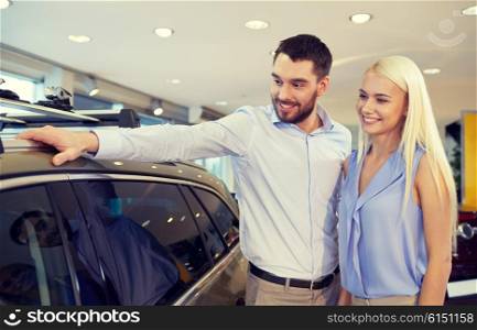 auto business, car sale, consumerism and people concept - happy couple buying car in auto show or salon