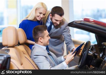 auto business, car sale, consumerism and people concept - happy couple with car dealer in auto show or salon