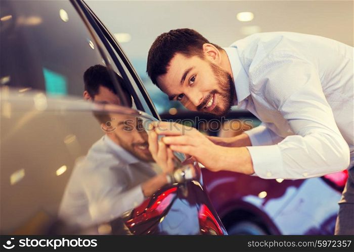 auto business, car sale, consumerism and people concept - happy man touching car in auto show or salon