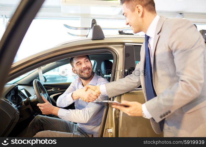 auto business, car sale, consumerism, gesture and people concept - happy man with car dealer making deal and shaking hands in auto show or salon